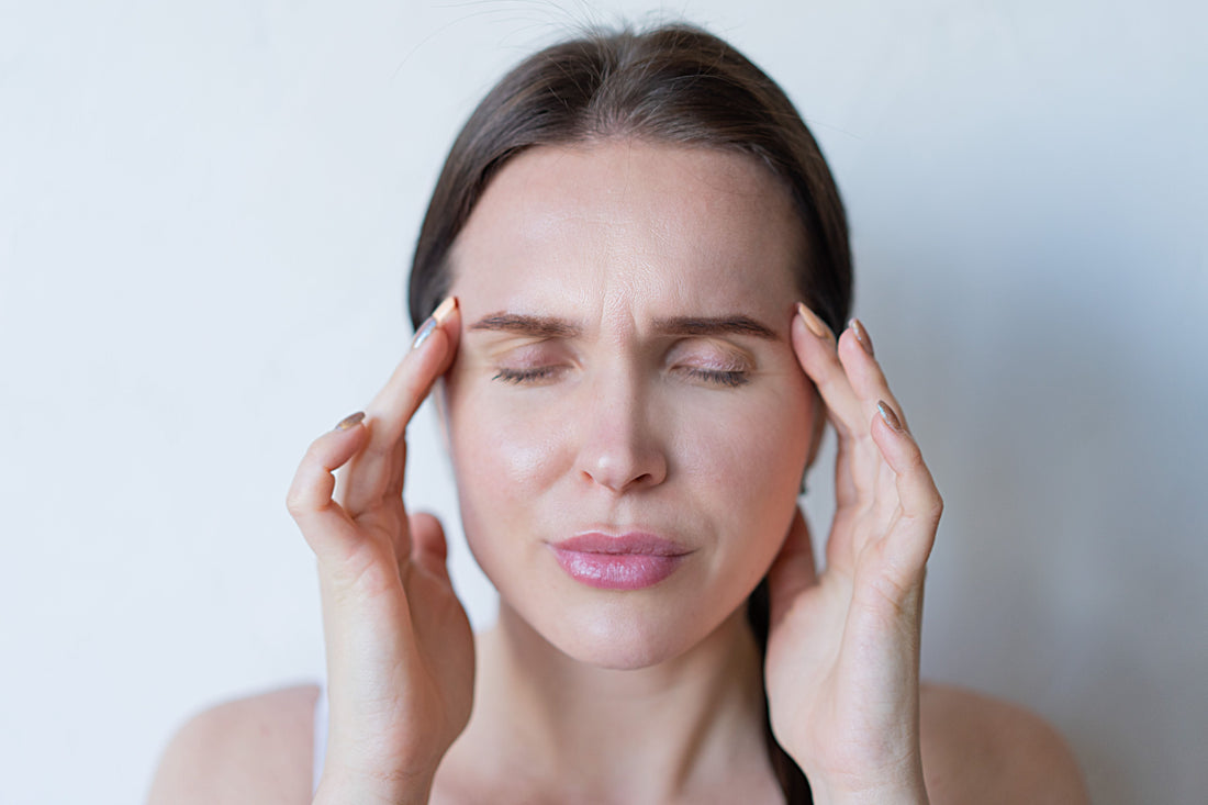 Woman with her eyes closed holding her temples while feeling unwell