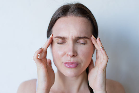 Woman with her eyes closed holding her temples while feeling unwell