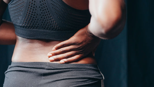 Person holding the lower back and tailbone area in discomfort
