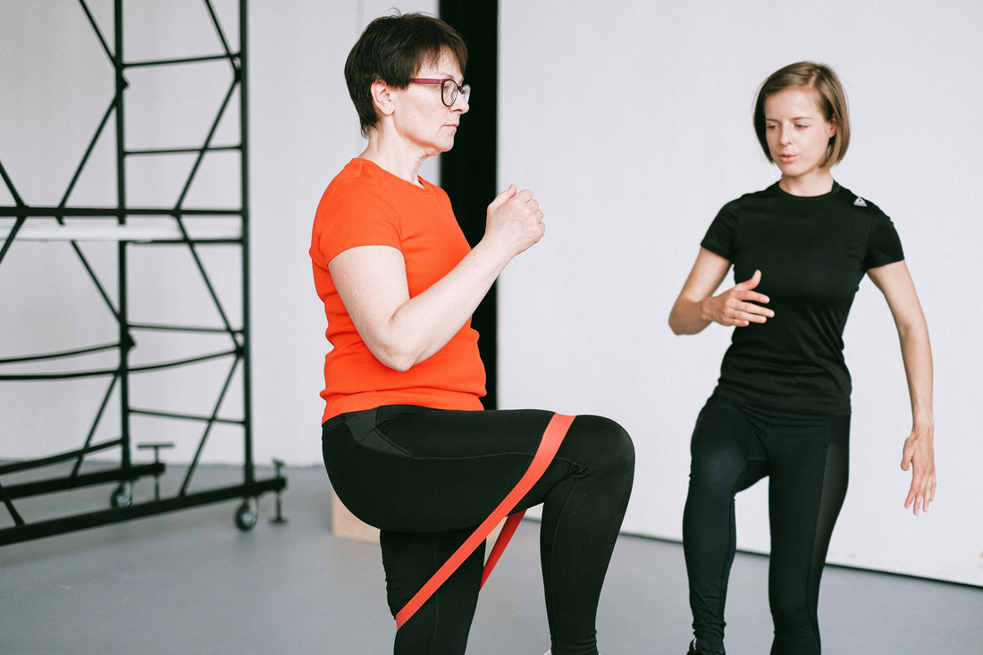 Physiotherapist guiding a woman through a resistance band shoulder exercise