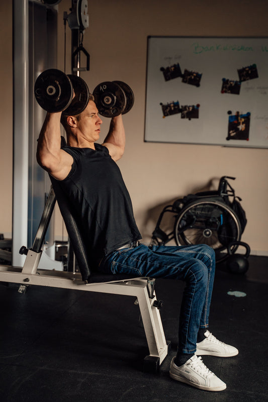 Man performing a dumbbell shoulder press in a gym
