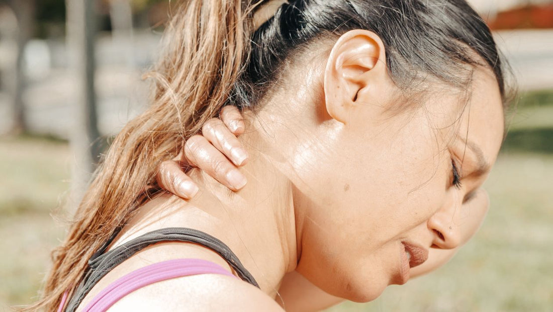Woman holding the back of her neck outdoors