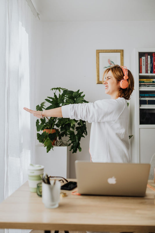 Woman taking a movement break while working at a laptop in a home office